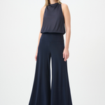 Woman wearing a navy sleeveless top and wide-leg pants on a white background