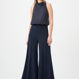 Woman wearing a navy sleeveless top and wide-leg pants on a white background