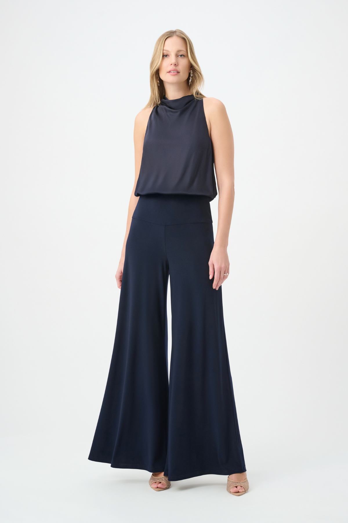 Woman wearing a navy sleeveless top and wide-leg pants on a white background