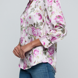 Model wearing rose print blouse with jeans on white background.