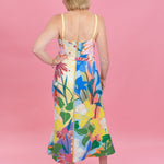 Woman wearing a colorful floral dress against a pink background