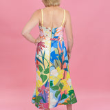 Woman wearing a colorful floral dress against a pink background