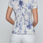 Person wearing a floral patterned shirt and white pants on a plain background