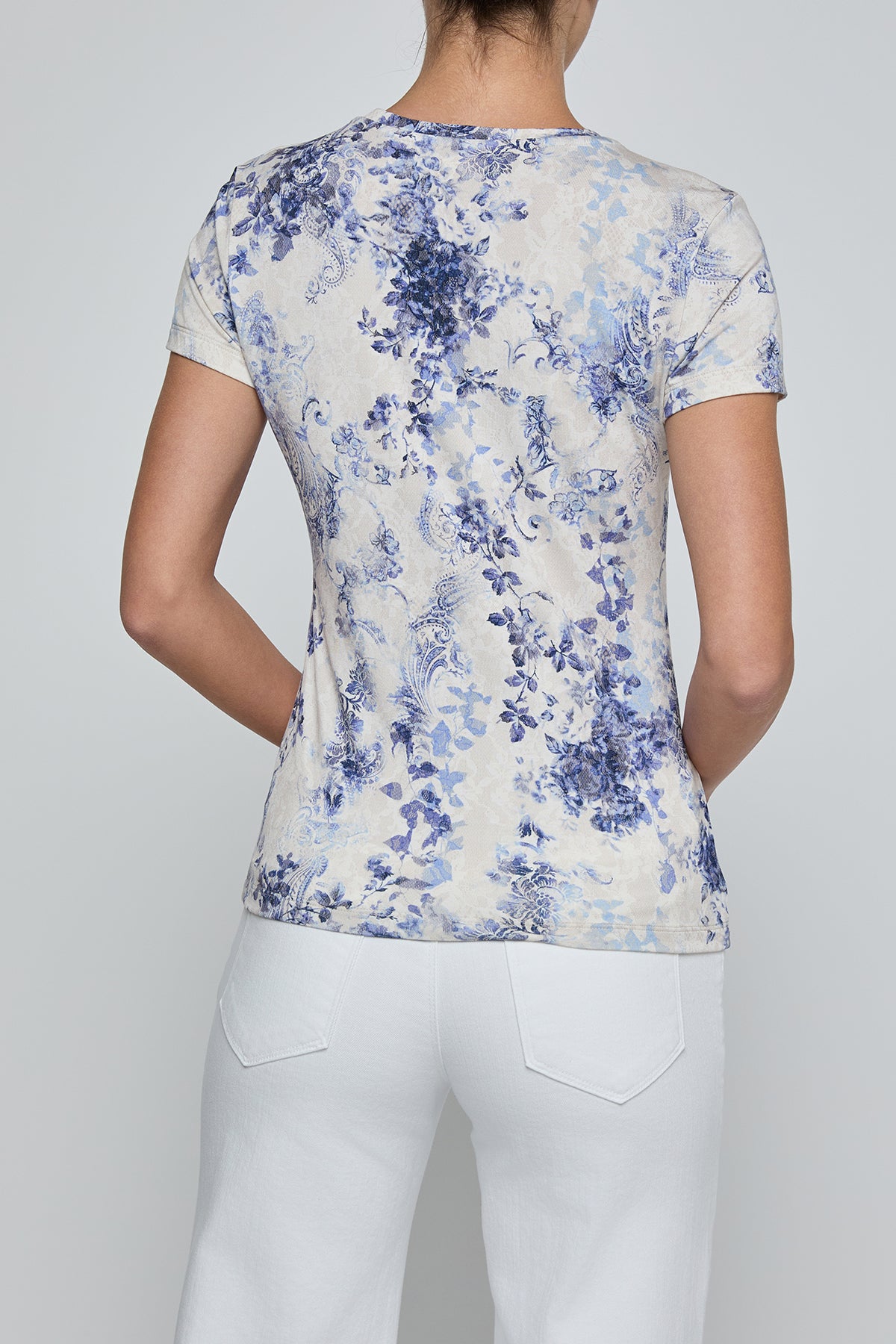 Person wearing a floral patterned shirt and white pants on a plain background