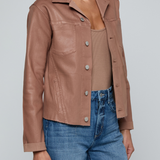Model wearing a light-wash slim-fit denim jacket with raw hem detailing and a button-front design.