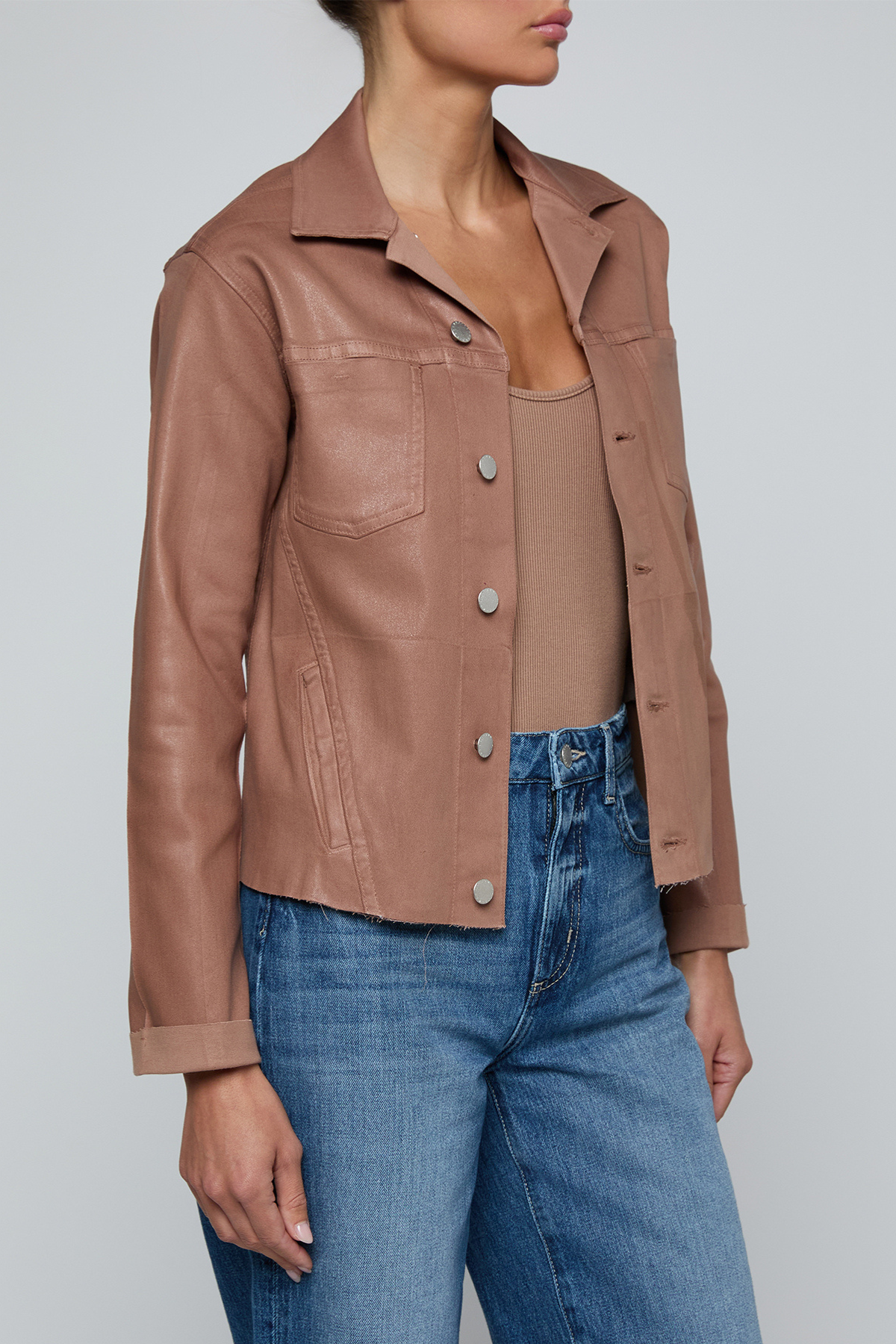 Model wearing a light-wash slim-fit denim jacket with raw hem detailing and a button-front design.