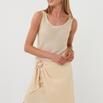 Woman wearing a beige sleeveless top and skirt on a white background