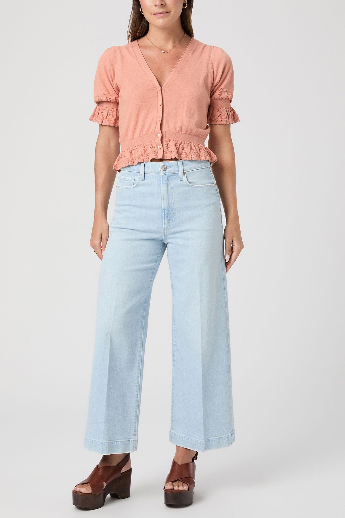 Woman wearing a pink blouse and light blue jeans on a white background