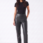A woman modeling a pair of black faux-leather straight-leg pants, paired with a black short-sleeve t-shirt and black pointed-toe mule heels, against a plain white studio background.
