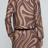 A model shown from the back wearing a matching cropped jacket and skirt set with a brown, beige, and dusty pink wavy abstract pattern.