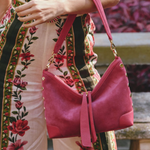 Person holding a pink handbag with a floral dress in the background