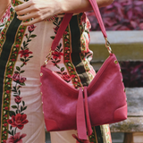 Person holding a pink handbag with a floral dress in the background