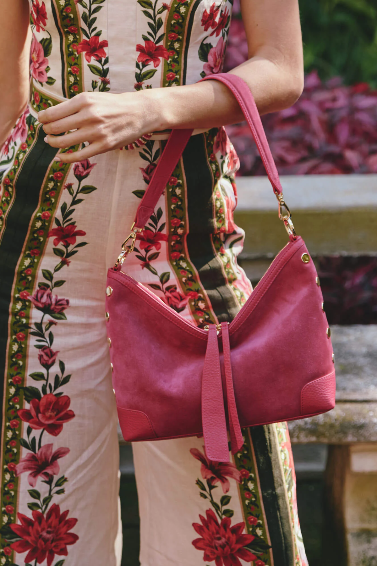 Person holding a pink handbag with a floral dress in the background