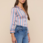 Woman wearing a striped shirt and jeans against a beige background