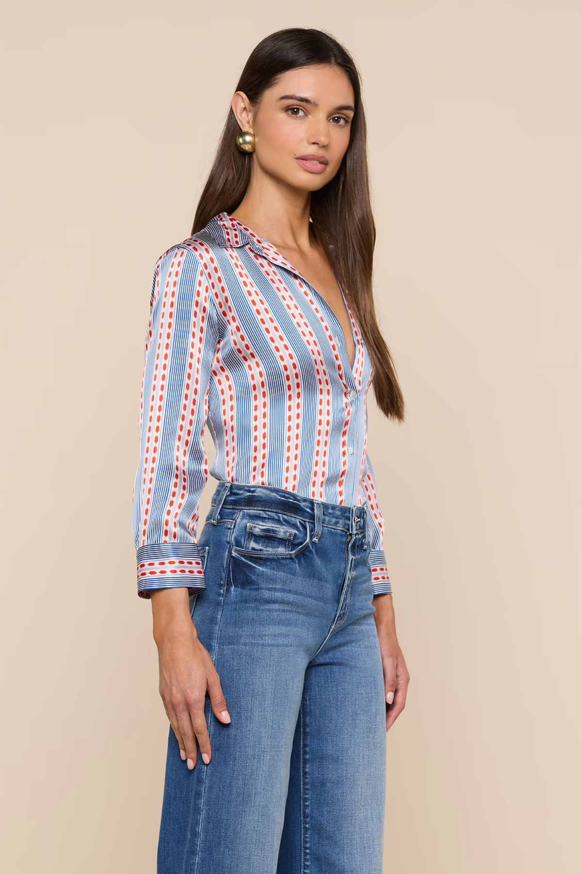 Woman wearing a striped shirt and jeans against a beige background