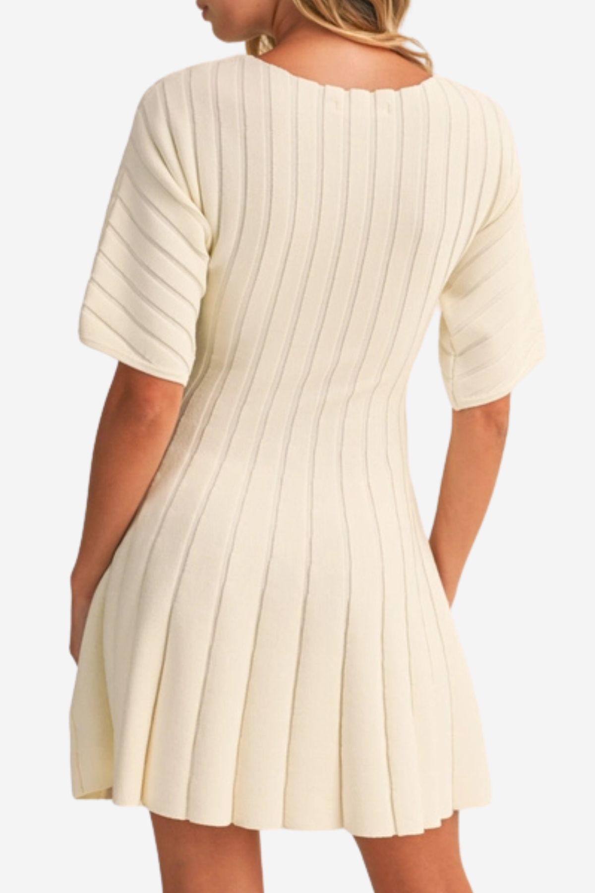 A woman wearing a cream-colored ribbed knit dress with pleated details, shown from the back against a plain white background.