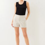 Woman wearing a black sleeveless top and white shorts on a plain background