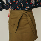 Person wearing a floral blouse and olive green skirt on a neutral background