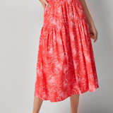 Woman wearing a red dress with white patterns on a gray background