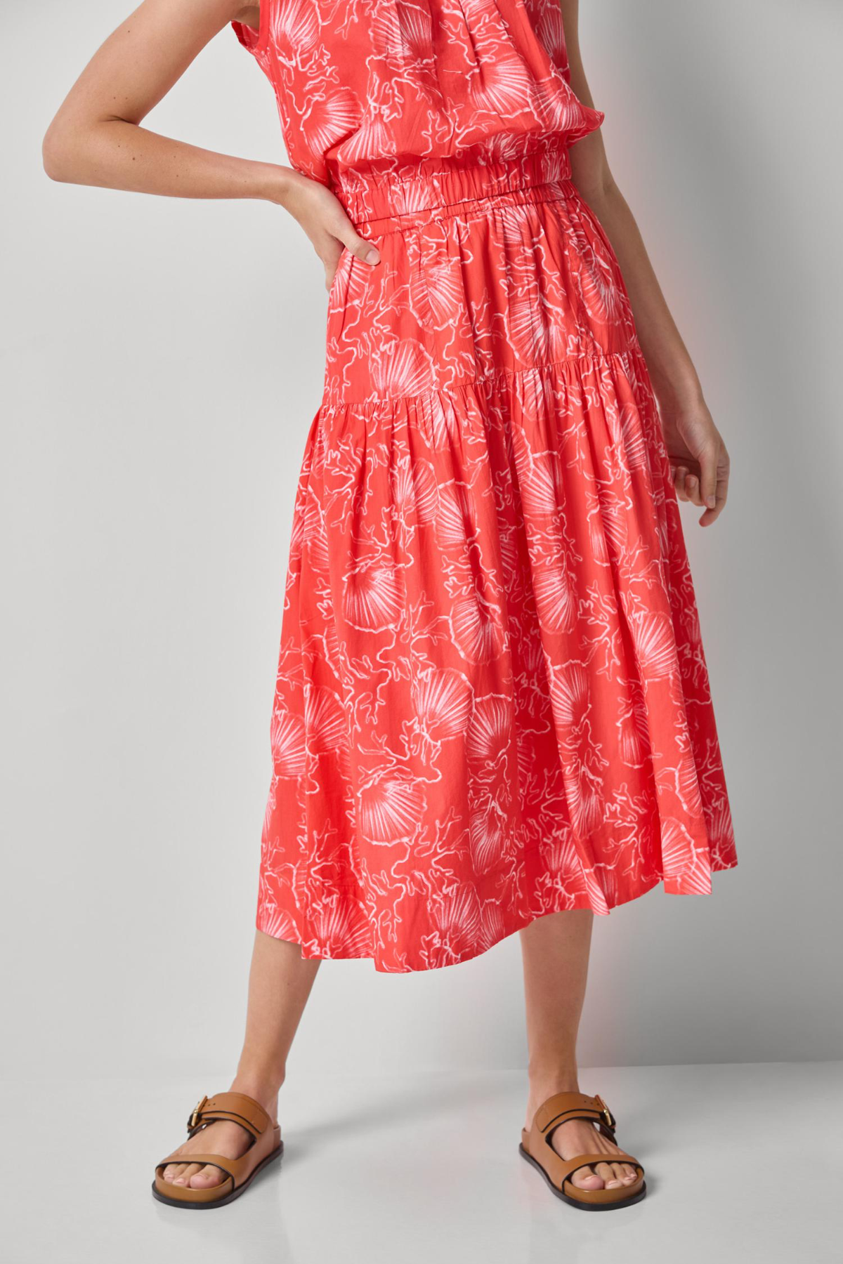 Woman wearing a red dress with white patterns on a gray background