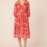 Woman wearing a red patterned dress on a beige background