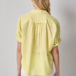 Person wearing a yellow shirt and white pants on a gray background
