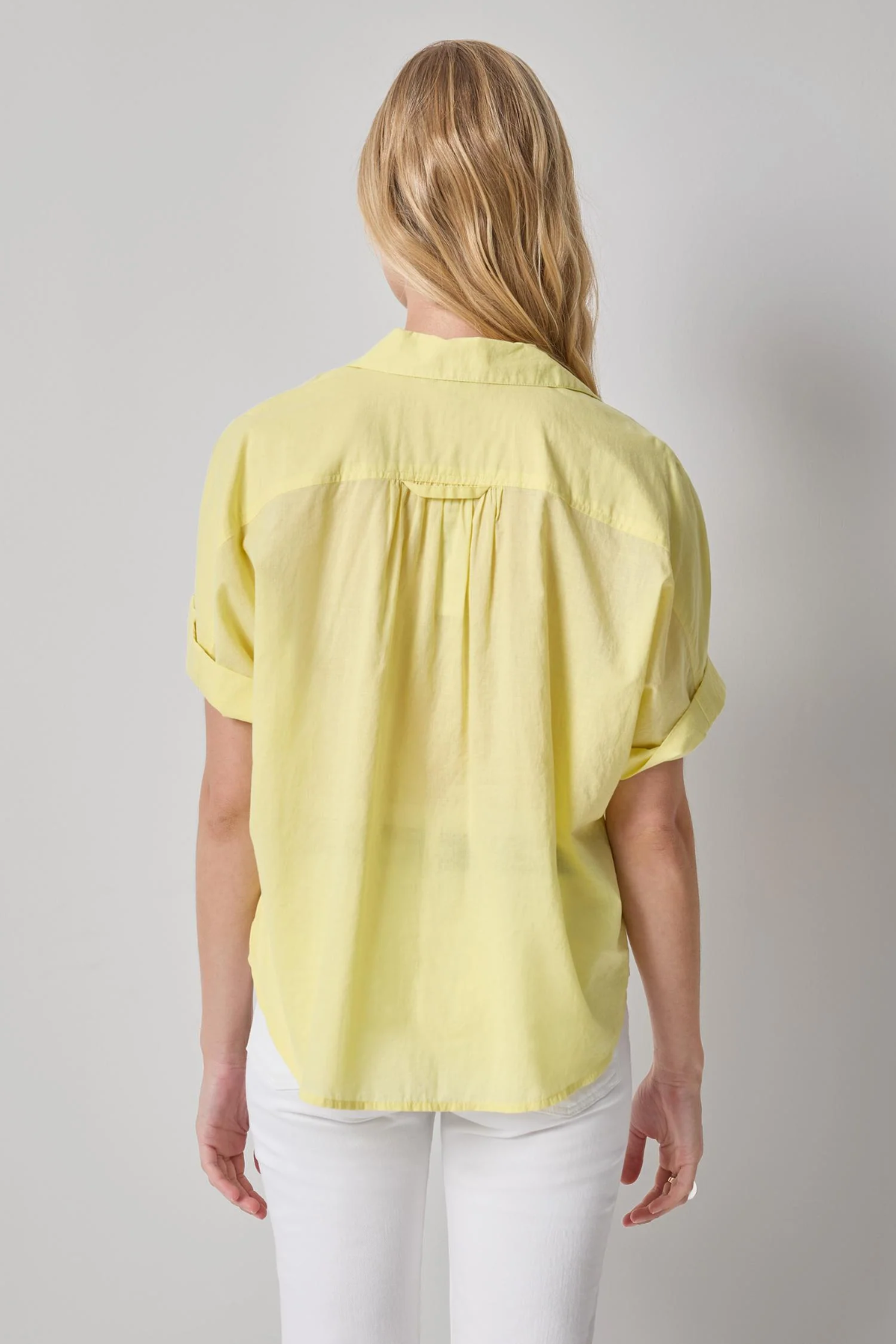 Person wearing a yellow shirt and white pants on a gray background