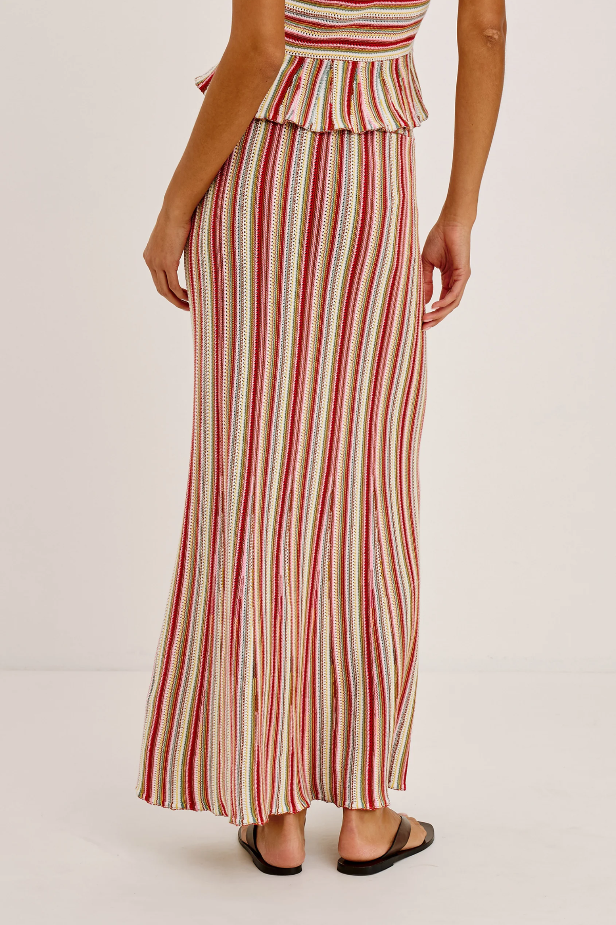 Woman wearing a red and white striped skirt on a plain background