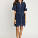 Model wearing a navy lace tie waist dress on an off white background.