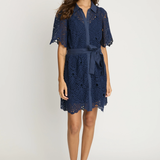 Model wearing a navy lace tie waist dress on an off white background.
