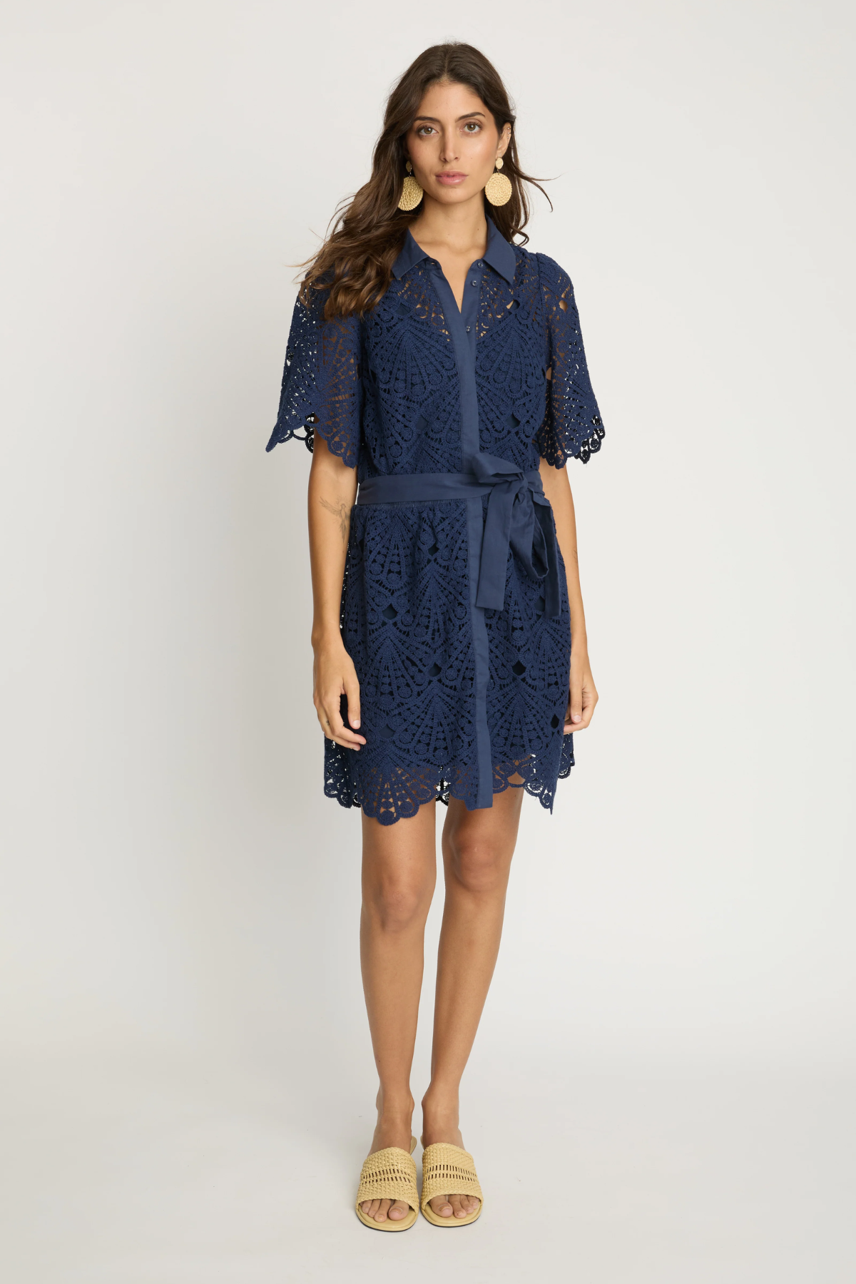 Model wearing a navy lace tie waist dress on an off white background.