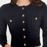 Black cropped cardigan with gold buttons worn by a person on a white background