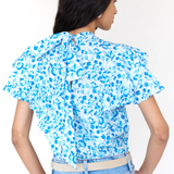 Woman wearing a blue floral blouse and jeans on a white background