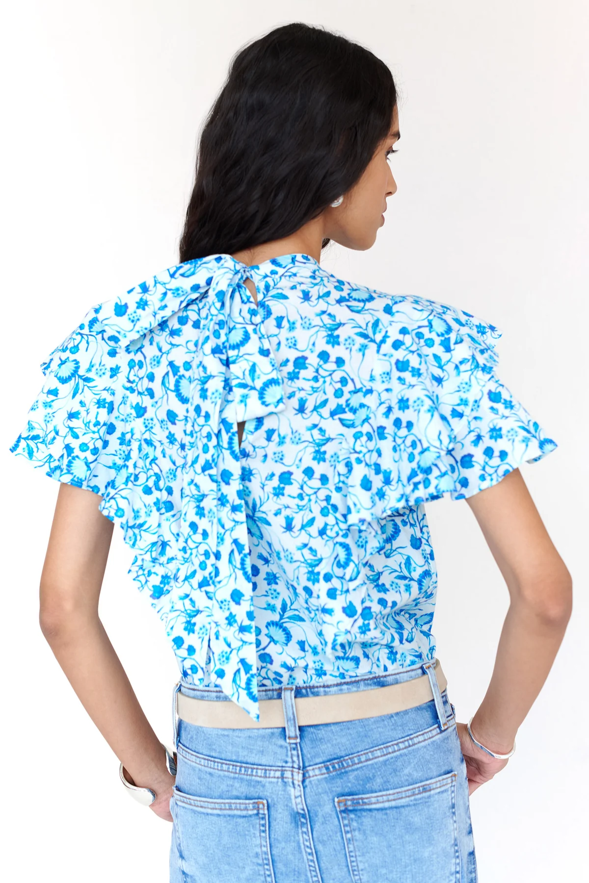 Woman wearing a blue floral blouse and jeans on a white background