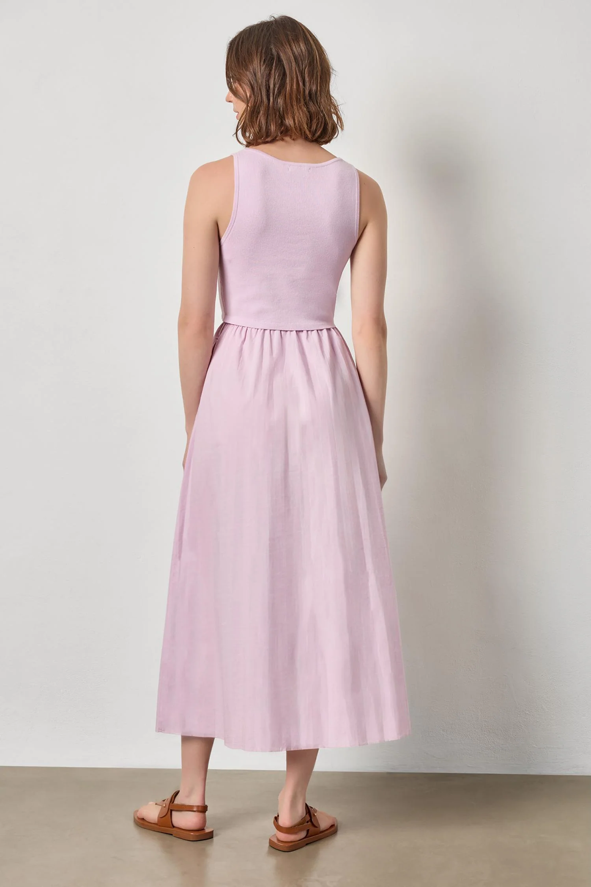 Woman wearing a light pink sleeveless dress against a plain background