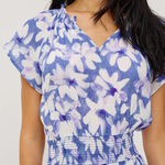 Woman wearing a blue floral dress against a white background