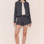 Woman wearing a jacket and shorts set with a white shirt on a plain background