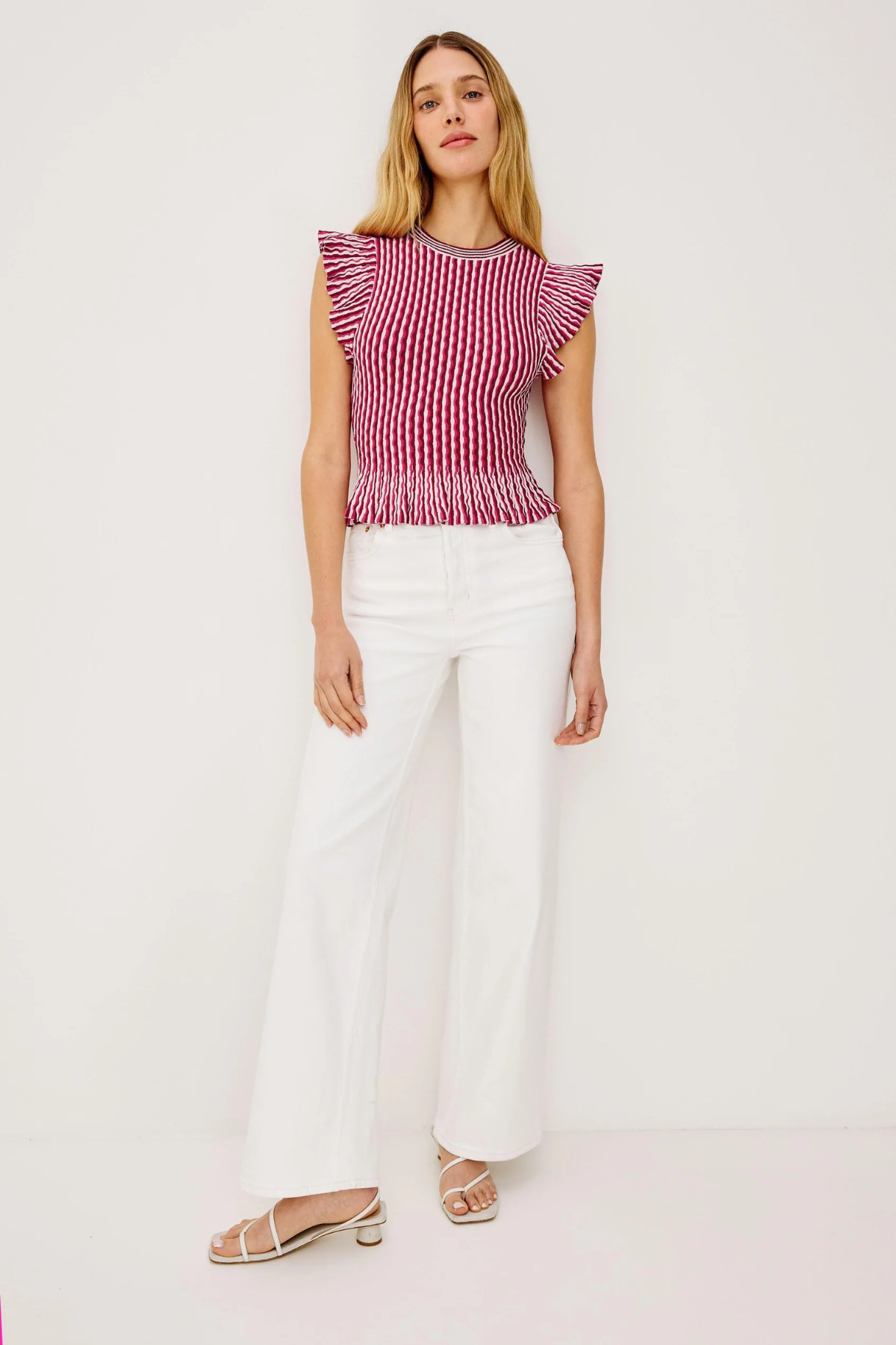 Woman wearing a red and white striped top with white pants on a white background