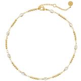 A delicate gold chain necklace with small oval clear stones spaced along the chain, displayed on a clean white background.
