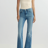 Person wearing a cream top and blue flared jeans on a white background