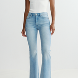 Person wearing light blue flared jeans and a white top on a white background