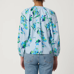 Person wearing a light blue floral blouse and jeans on a white background