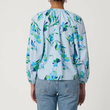 Person wearing a light blue floral blouse and jeans on a white background