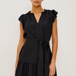 Woman wearing a black dress with ruffled shoulders against a white background