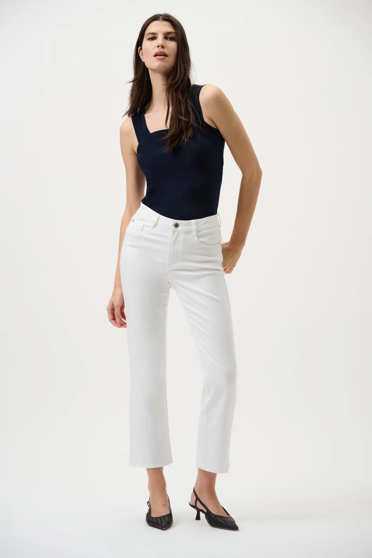 Woman wearing a black sleeveless top and white pants on a white background