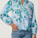 Woman wearing a floral blouse with blue jeans on a white background