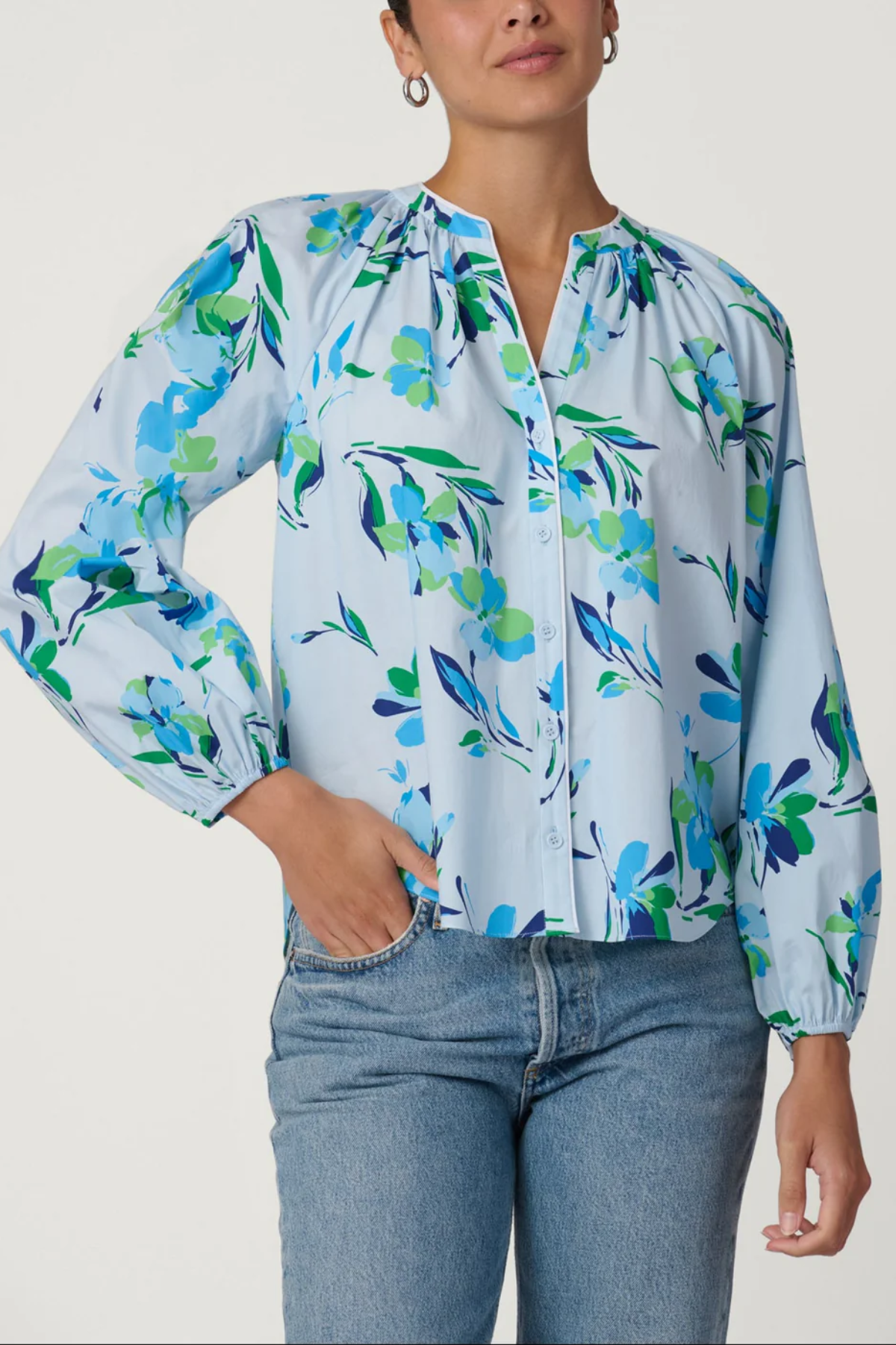Woman wearing a floral blouse with blue jeans on a white background
