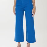 Person wearing blue pants and black strappy shoes on a white background