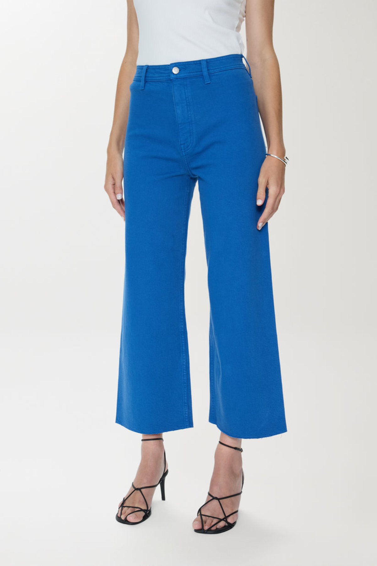 Person wearing blue pants and black strappy shoes on a white background