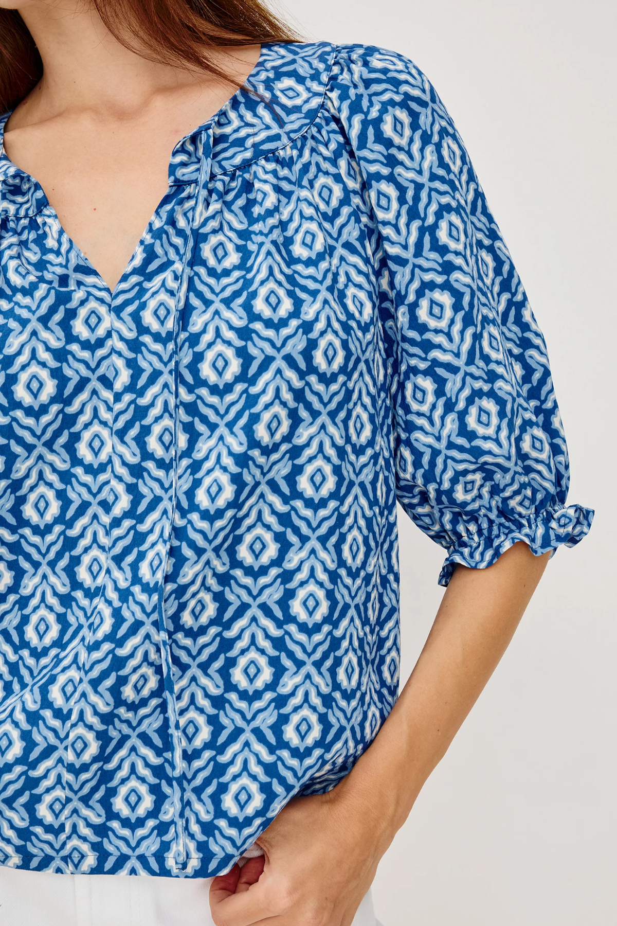 close up on woman in blue printed blouse on white background 